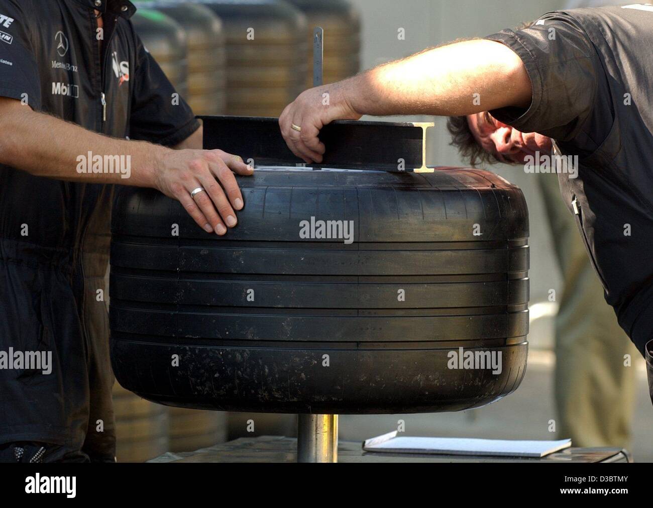 (Dpa) - i meccanici del team McLaren-Mercedes prendere meticolosamente la misura di gomme da gara, alla gara di Formula Uno in pista a Monza, Italia, 11 settembre 2003. I nuovi pneumatici Michelin sembrano essere conformi con la motor sport regole. Il mondo della Formula Uno il corpo direttivo, la FIA ha dato la McLaren e Williams il g Foto Stock