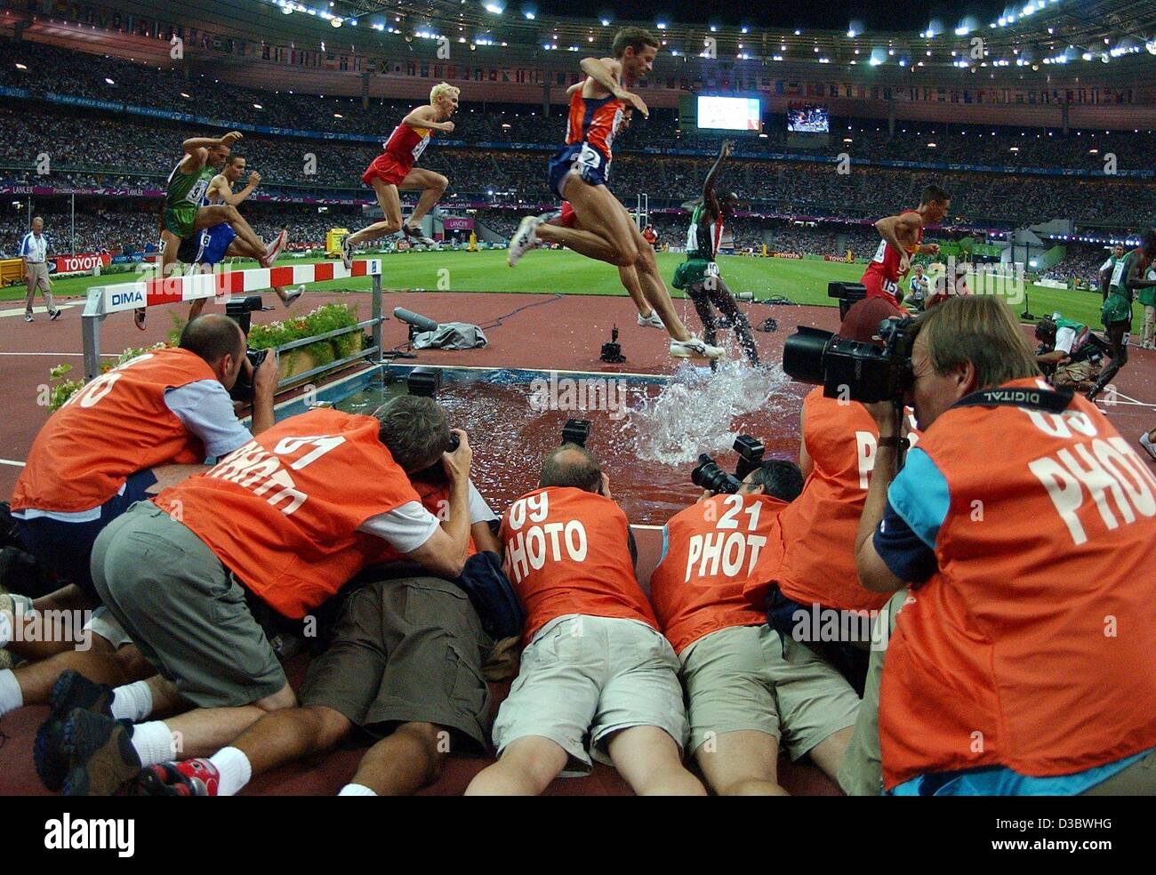 (Dpa) - Un gruppo di fotografi si affollano intorno il fossato come gli atleti chiaro un ostacolo durante la 3000m Siepi evento presso il nono IAAF Atletica Campionati del Mondo allo Stade de France di Parigi, 23 agosto 2003. Foto Stock