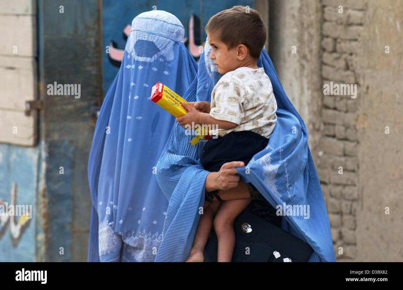 (Dpa) - Due donne che indossano il tradizionale blu burka velo trasportare un bambino lungo una strada a Kabul, Afghanistan, 4 agosto 2003. Dal momento che la caduta del regime dei talebani il burka, che ricopre completamente il corpo e la testa non è obbligatoria per le donne nel pubblico qualsiasi altro. Ma gli osservatori vedere il velo come indicato Foto Stock