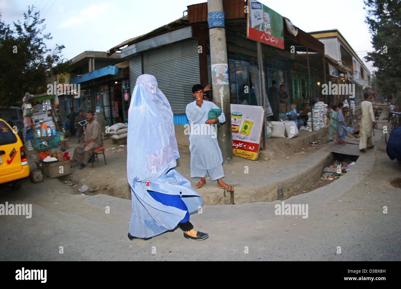 (Dpa) - Una donna afghana che indossano il tradizionale blu burka velo passa i venditori ambulanti e negozi in una strada a Kabul, Afghanistan, 4 agosto 2003. Dal momento che la caduta del regime dei talebani il burka, che ricopre completamente il corpo e la testa non è obbligatoria per le donne nel pubblico qualsiasi altro. Ma gli osservatori vedere th Foto Stock