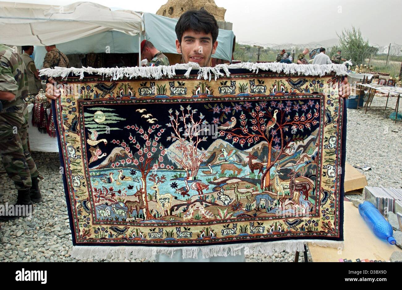 (Dpa) - Un venditore mostra un tappeto per la vendita al mercato delle pulci nei pressi dell'aeroporto a Kabul, Afghanistan, 3 agosto 2003. Sul mercato settimanale tutto da tappeti e gioielli di copie pirata di CD e DVD è disponibile. Foto Stock