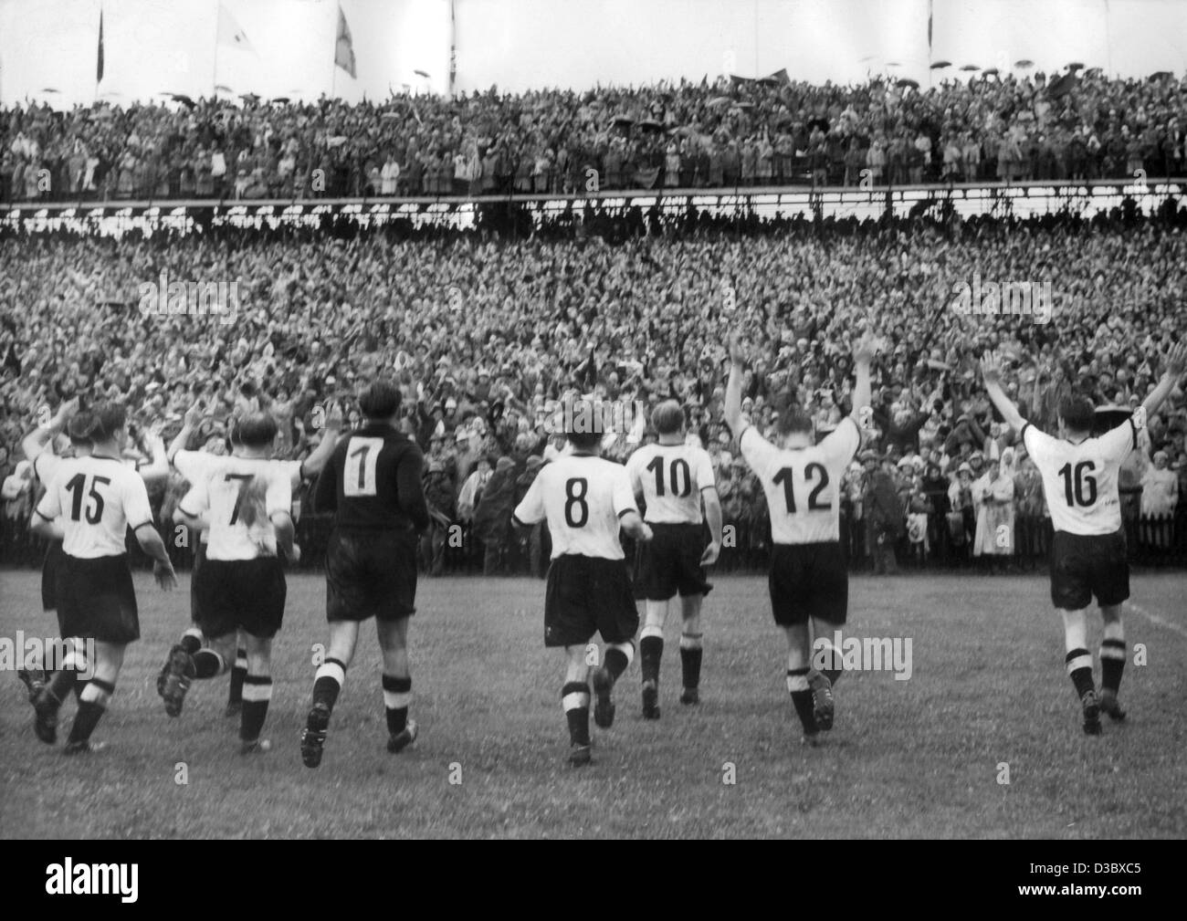 (Dpa) file - i membri della nazionale tedesca di calcio (L) Ottmar Walter (n. 15), Jupp Posipal (n. 7), Toni Turek (n. 1), Karl Mai (n. 8), Werner Liebrich (n. 10), Helmut Rahn (n. 12) e Fritz Walter (n. 16) a piedi attraverso il passo e si presentano dopo aver vinto il Mondiale 1954 Cham Foto Stock