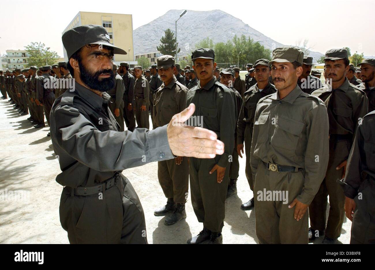 (Dpa) - Un istruttore dimostra di colonne della polizia afgana reclute come marzo, salutare e stand presso l attenzione sulla parade-massa dell'Accademia di polizia di Kabul, Afghanistan, 4 Agosto 2003.La responsabilità della sicurezza pubblica si trova con la sicurezza internazionale Assistance Force (ISAF) che è Foto Stock