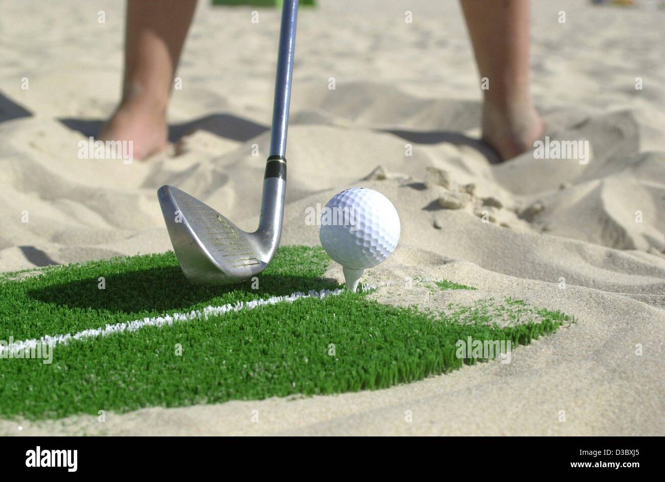 (Dpa) - un golfista svolge un tee-off sulla Spiaggia di Ahlbeck sull'isola di Usedom, Germania, 4 agosto 2003. Dietro volleyballers golfisti stanno scoprendo la spiaggia come un luogo perfetto per il loro sport. Tuttavia, beach golf non è riprodotto nella sabbia, ma su un mobile manti erbosi sintetici. La 120 mq artifi Foto Stock