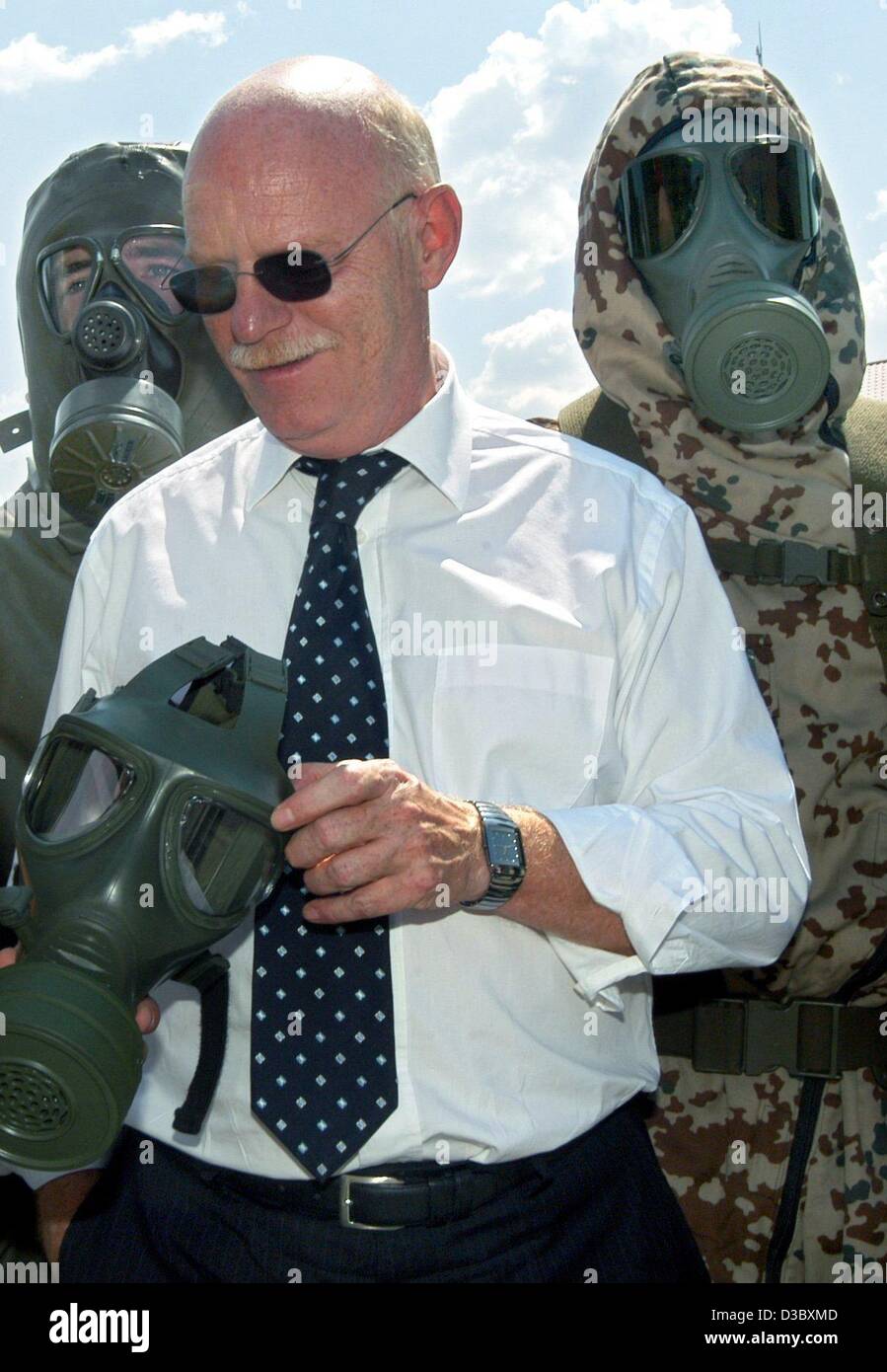 (Dpa) - Tedesco il Ministro della Difesa Peter Struck guarda alla NBC (armi nucleari, biologiche e chimiche) maschera mentre due soldati in abbigliamento protettivo e maschere di ossigeno sono in piedi dietro di lui, a Sonthofen in Germania, 8 agosto 2003. Il Ministro ha visitato la protezione NBC scuola della Bundeswehr assortiti Foto Stock