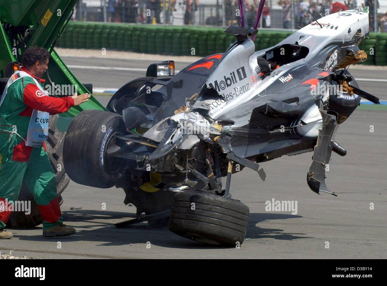 (Dpa) - il relitto della McLaren-Mercedes race car di finitura pilota di Formula Uno Kimi Raeikkoenen viene rimossa dopo un incidente alla partenza del Gran Premio di Formula Uno di Germania a Hockenheim gara via, Germania, 3 agosto 2003. Raeikkoenen non è stato ferito. Foto Stock