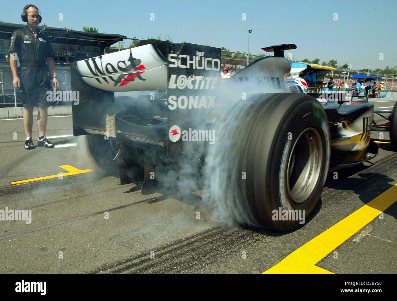 (Dpa) - Finlandese pilota di Formula Uno Kimi Raeikkoenen della McLaren Mercedes è spento in una nuvola di fumo come egli inizia dalla fossa durante la prima formazione gratuita su Hockenheim Anello pista di gara di Hockenheim, in Germania, 1 agosto 2003. La dodicesima marcia di campionati del mondo, il Gran Premio di Germania, Foto Stock