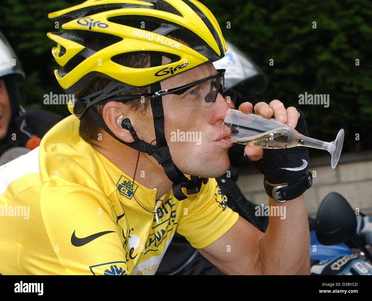 (Dpa) - Noi Postal-Berry pavimento è Lance Armstrong da noi, indossando il leader globale la maglia gialla, gode di un bicchiere di champagne come egli cicli durante il ventesimo tappa del 2003 Tour de France corsa in bicicletta sulla sua via dei Champs Elysées a Parigi, il 27 luglio 2003. La gara finale della tappa domenicale in Pa Foto Stock