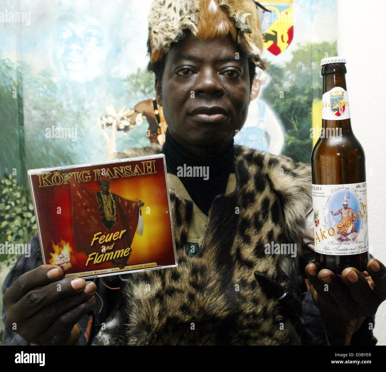 (Dpa) - Cefa Bansah, re della tribù degli Ewe nel Ghana e residenti in Germania, mostra il suo ultimo CD musicali e una bottiglia di birra chiara che mostra la sua immagine, nella sua casa di Ludwigshafen, Germania, 24 luglio 2003. Re Bansah ha già pubblicato due CD con party hits, e ora egli è di promuovere la sua nuova Foto Stock