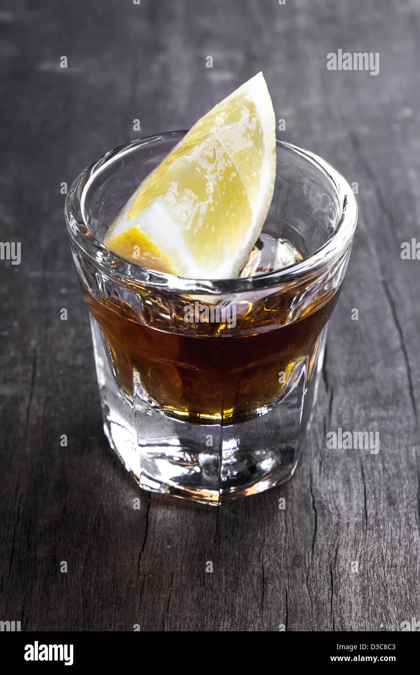 Singolo bicchiere di tequila con limone sul tavolo Foto Stock