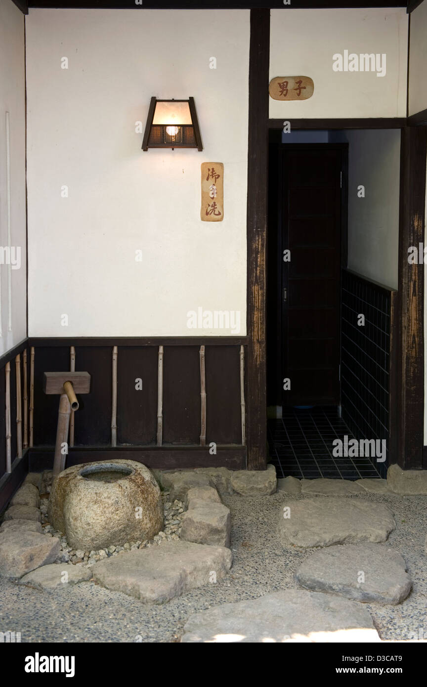 Entrata di stile giapponese uomini toilette pubblica o "onorevoli lavare a mano,' come segno dice, con tsukubai pietra bacino d'acqua. Foto Stock