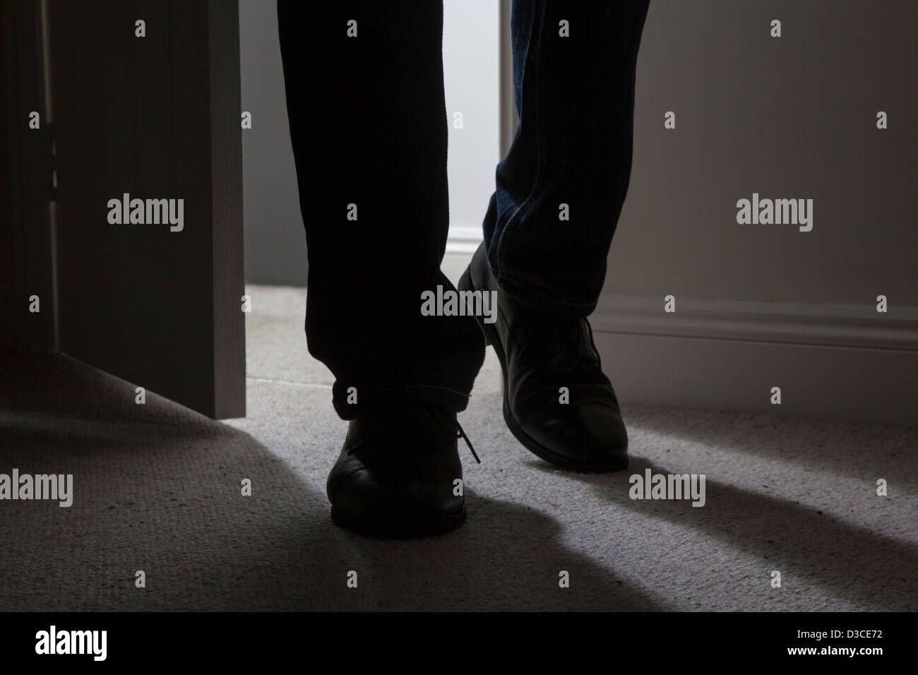 L'uomo entra in una stanza buia, retroilluminato colpo di gambe e piedi solo. Close up. Foto Stock