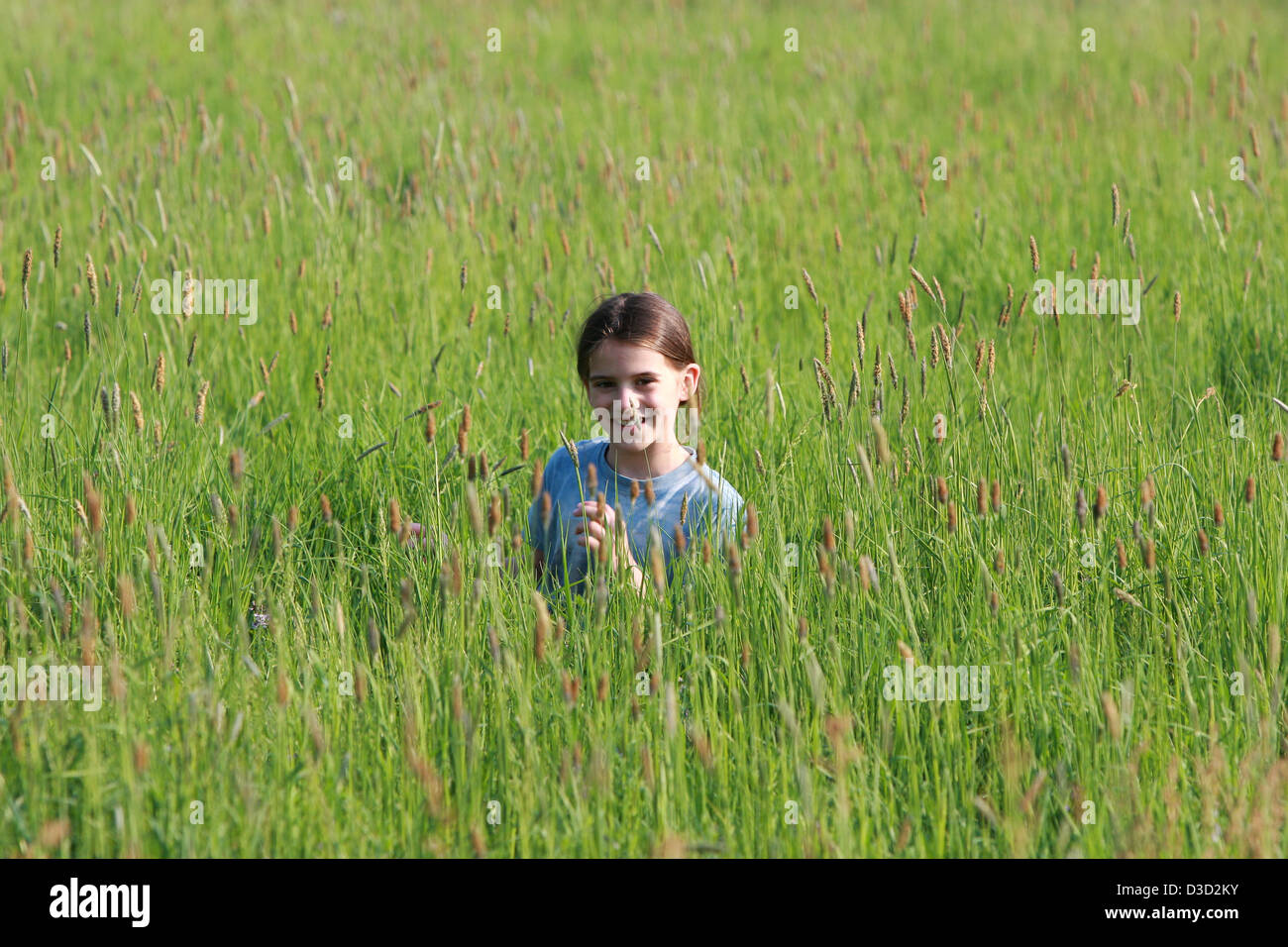 Leipzig, Germania, ragazza passa attraverso un campo di sorridere Foto Stock