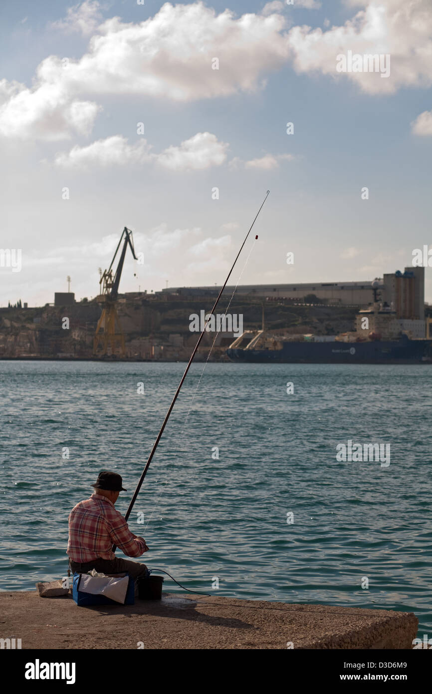 La Valletta, Malta, un pescatore sulla costa Foto Stock