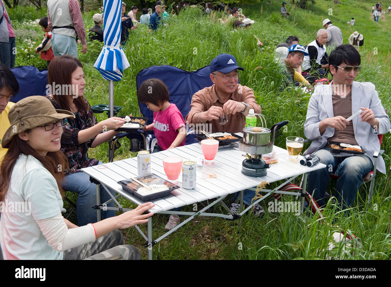 Outdoor picnic di famiglia in stile Giapponese con fold-up tavolo e sedie, camp stufa e molta birra. Foto Stock