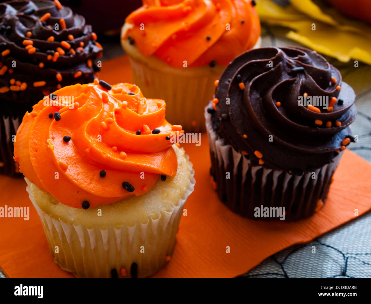 Tortini di Halloween con arancio e nero ciliegina sul tovagliolo arancio. Foto Stock