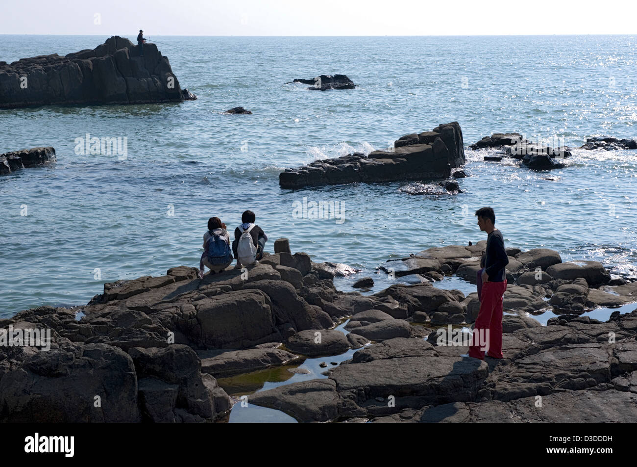 Pesca pescatore mentre i visitatori godere la vista del rocky, robusto Mare del Giappone costa in Tojinbo, Fukui, Giappone Foto Stock