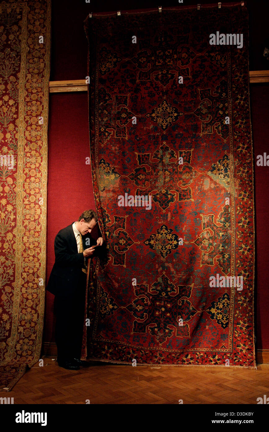 Londra, Inghilterra - Marzo 2004: Preparazione di tappeti tappeti per vendita a King Street. Christie's esperto William Robinson esamina il tappeto di tessitura. Foto Stock