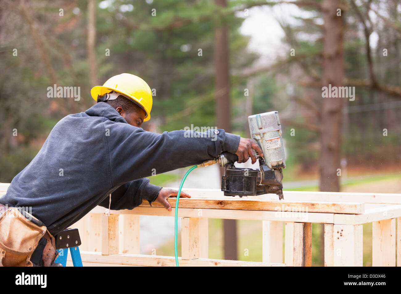 Carpenter utilizzando una pistola sparachiodi al telaio house Foto Stock