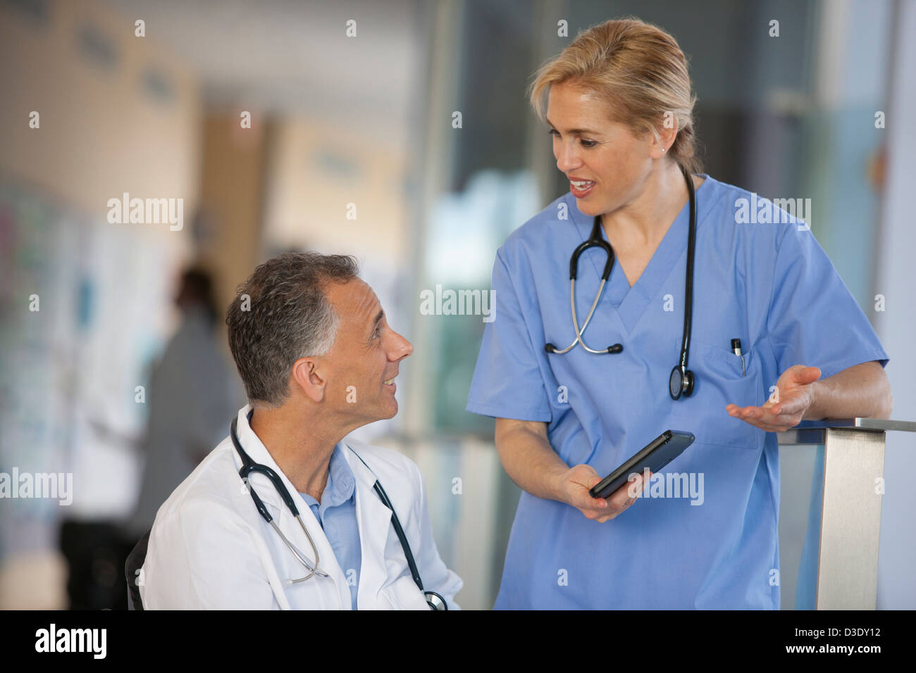 Dottore in carrozzella con lesioni del midollo spinale di parlare con un infermiere circa informazioni sul tablet Foto Stock