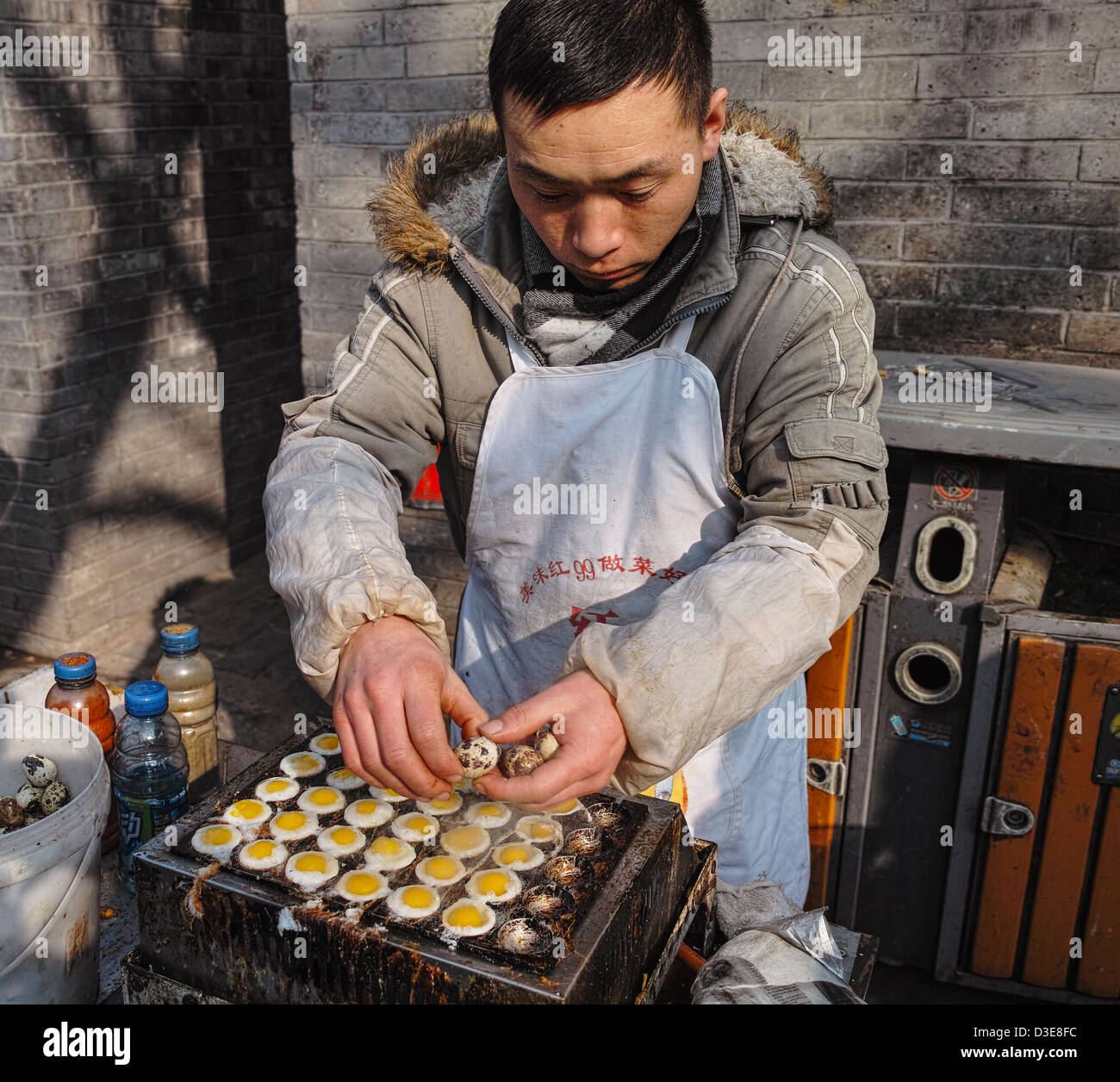 Un Cinese stallman cuocere il cibo locale in corrispondenza di una strada, Pechino Foto Stock