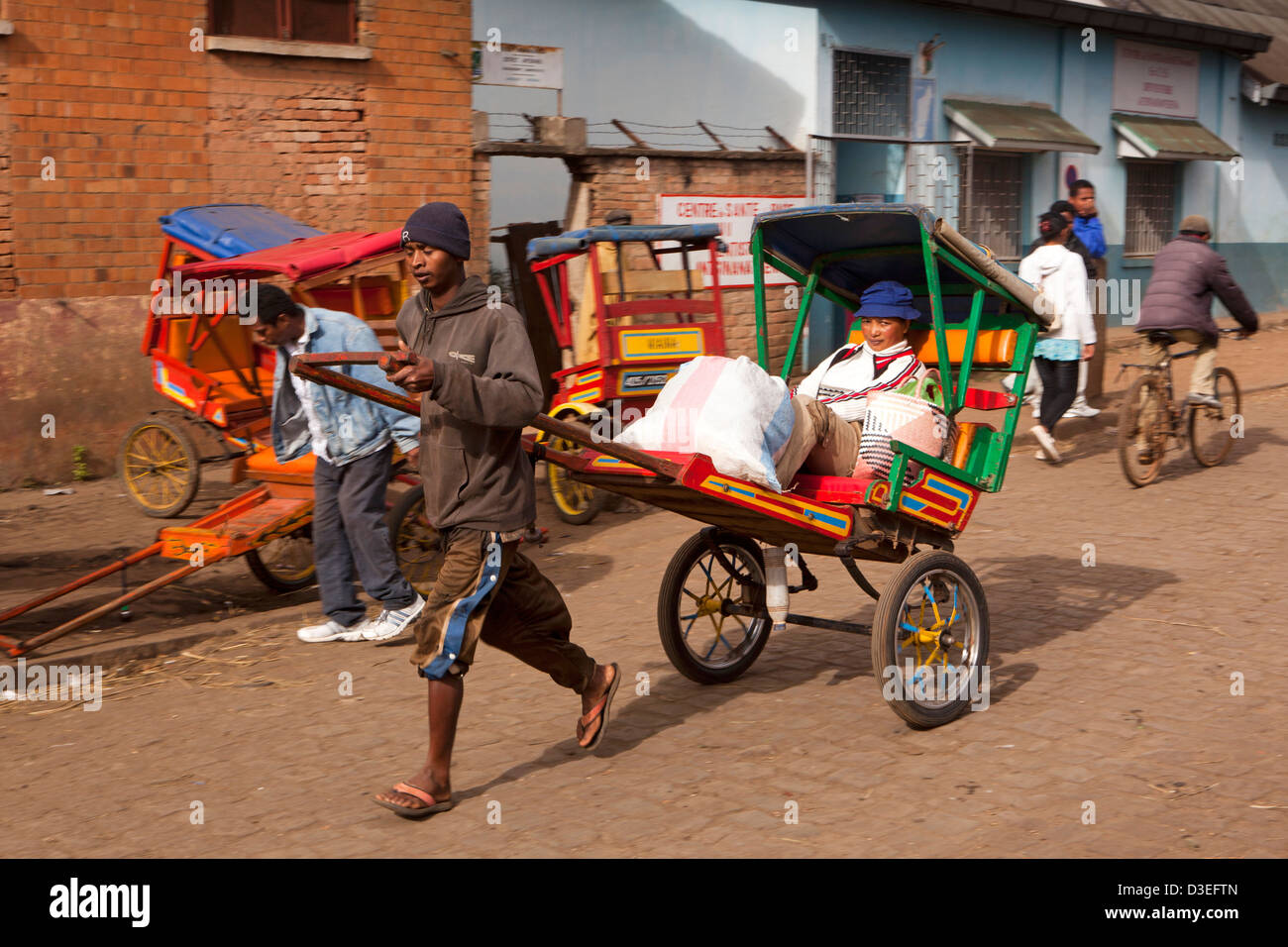 Madagascar, Antsirabe, Marche Sabotsy, passeggero in pousse-pousse uomo-tirato rickshaw Foto Stock