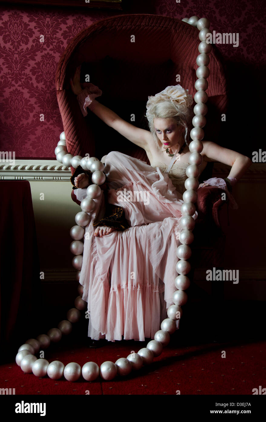Una principessa strega queen LADY donna in rosso e rosa castello con un gigante collana di perle in una fiaba surreale impostazione di fantasia Foto Stock