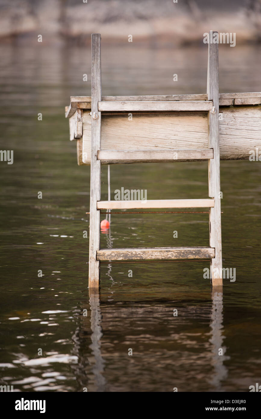 Tranquilla scena di pontile in legno con scaletta, rocce e acqua nell'arcipelago di Stoccolma, Svezia Foto Stock