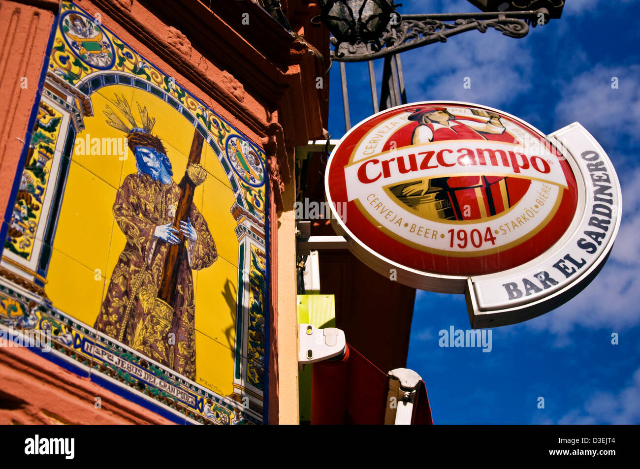Pubblicità per Cruzcampo birra presso il Bar El Sardinero a Siviglia accanto al murale in piastrelle di Cristo Foto Stock