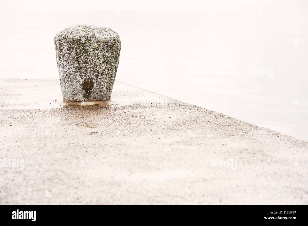 Tranquilla scena di dock di vuoto con pietra bollard e mare calmo Foto Stock