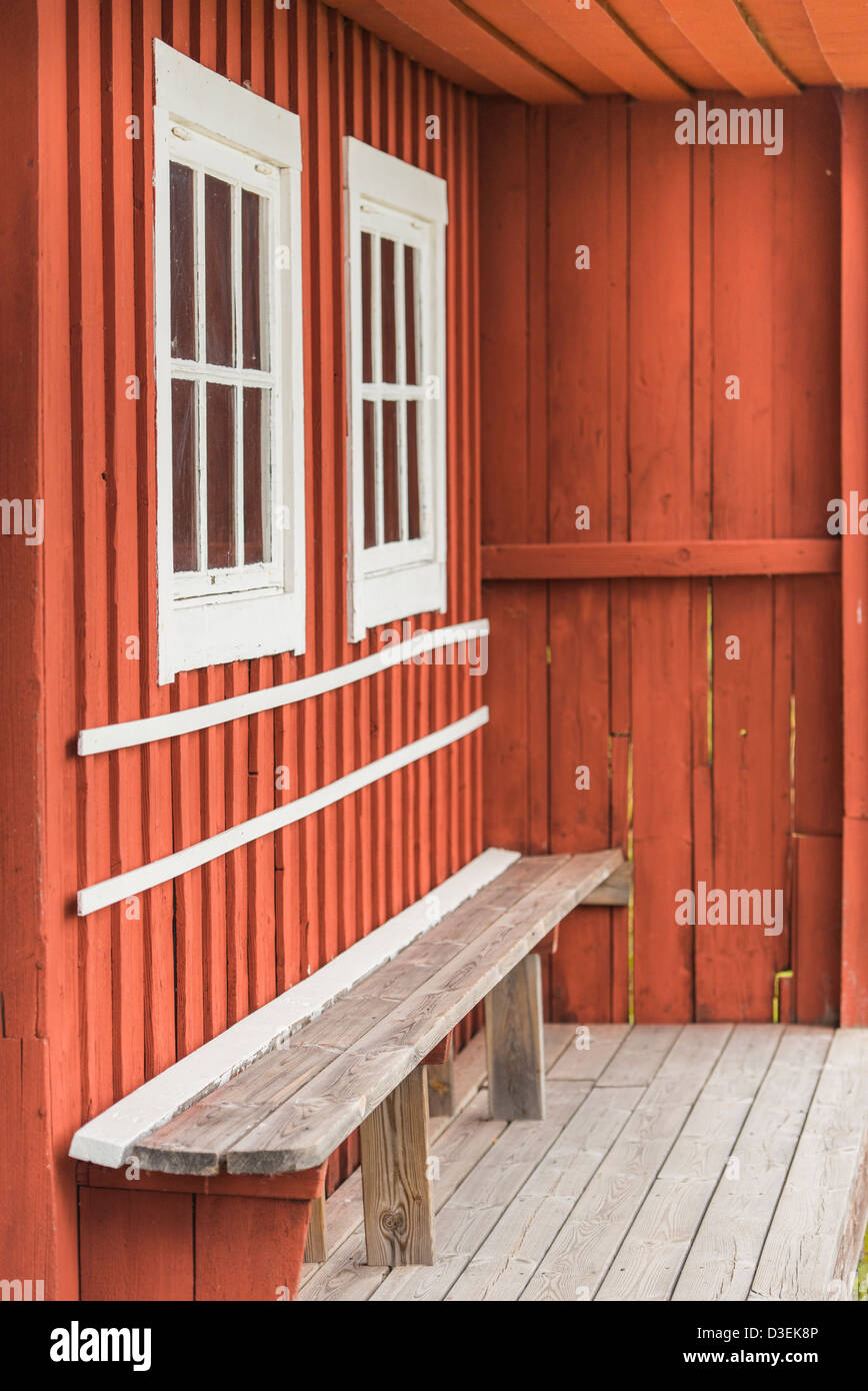 Svuotare panca in legno sulla parte anteriore portico di casa rossa nell'arcipelago di Stoccolma, Svezia Foto Stock