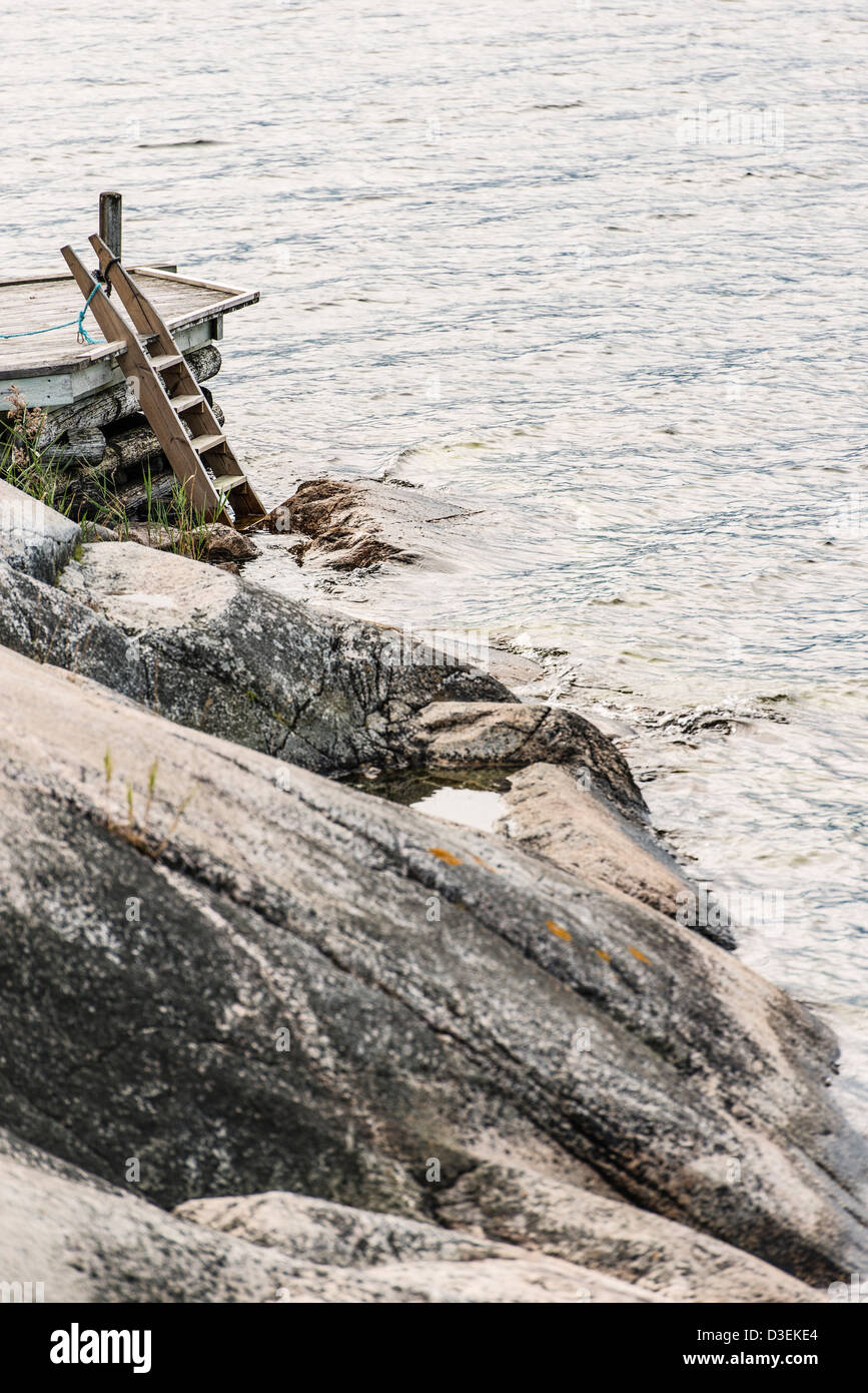 Tranquilla scena di pontile in legno con scaletta, rocce e mare nel arcipelago di Stoccolma, Svezia Foto Stock