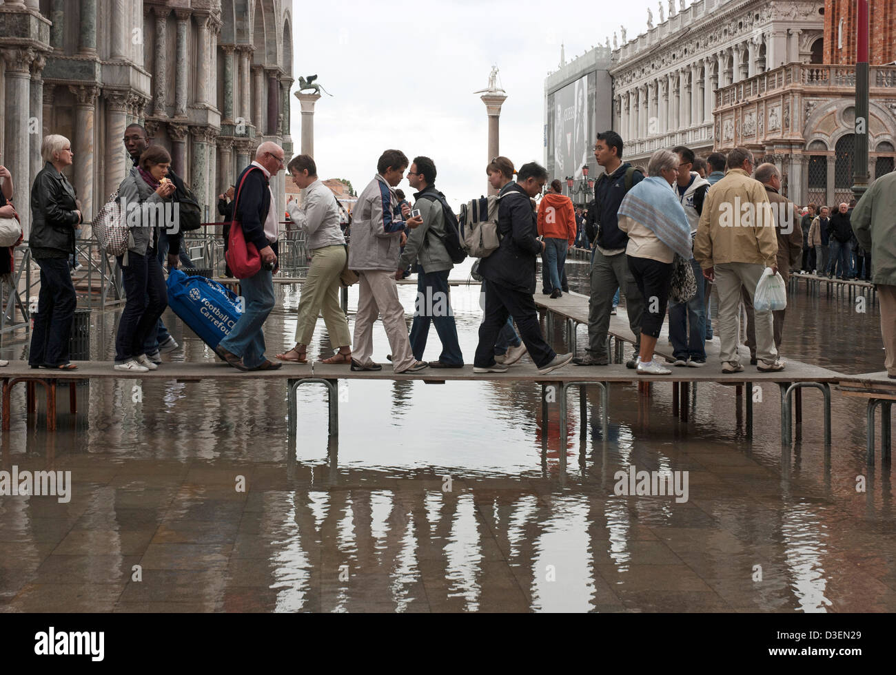 I turisti che visitano la cattedrale di San Marco allineando sulle piattaforme su acqua alta a Venezia Foto Stock