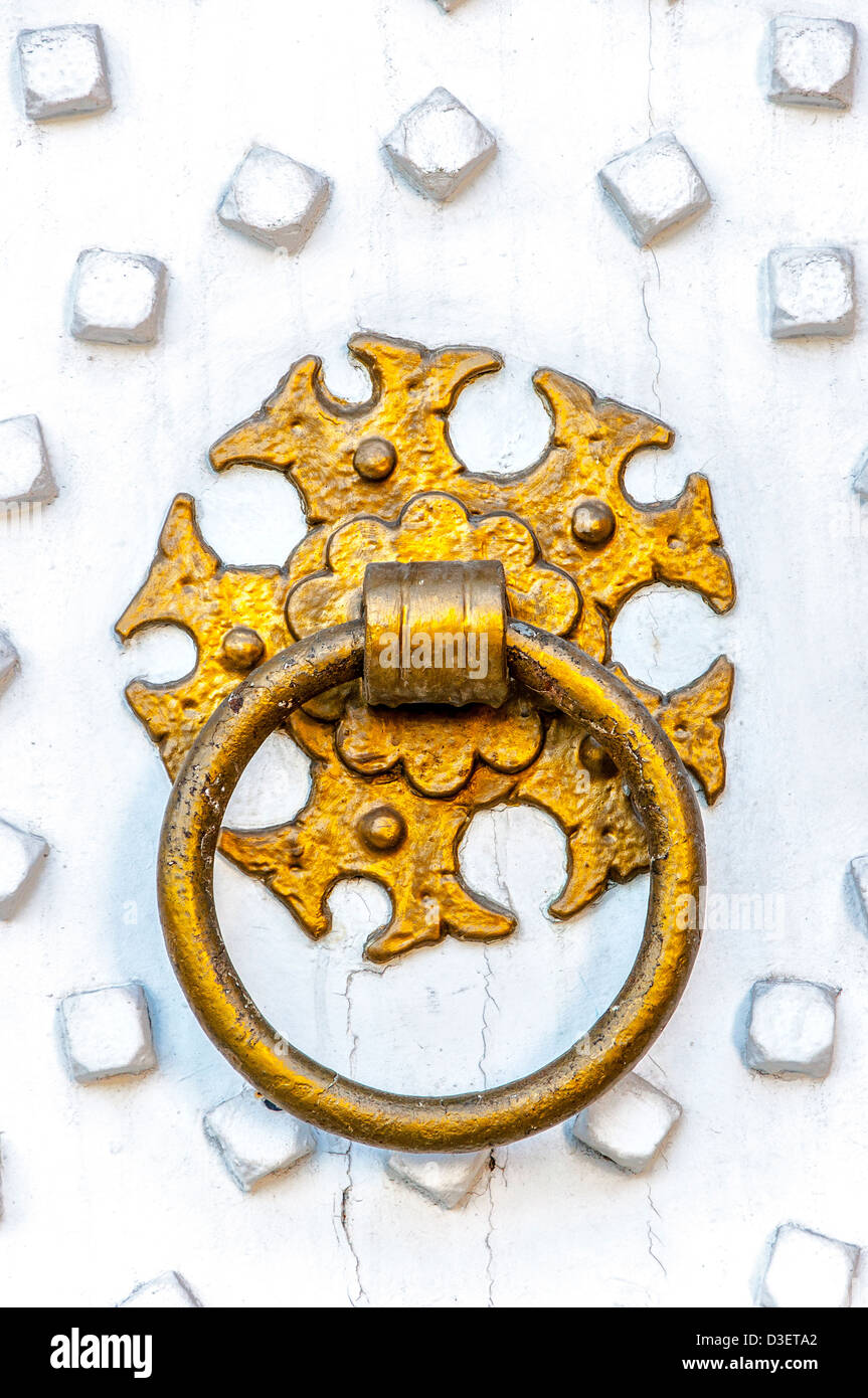 Un raffinato anello d'oro respingente su un luminoso dipinte di bianco porta in legno. Foto Stock