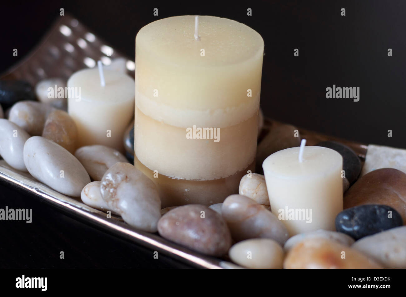 Tre candele in un piatto di pietre Foto Stock