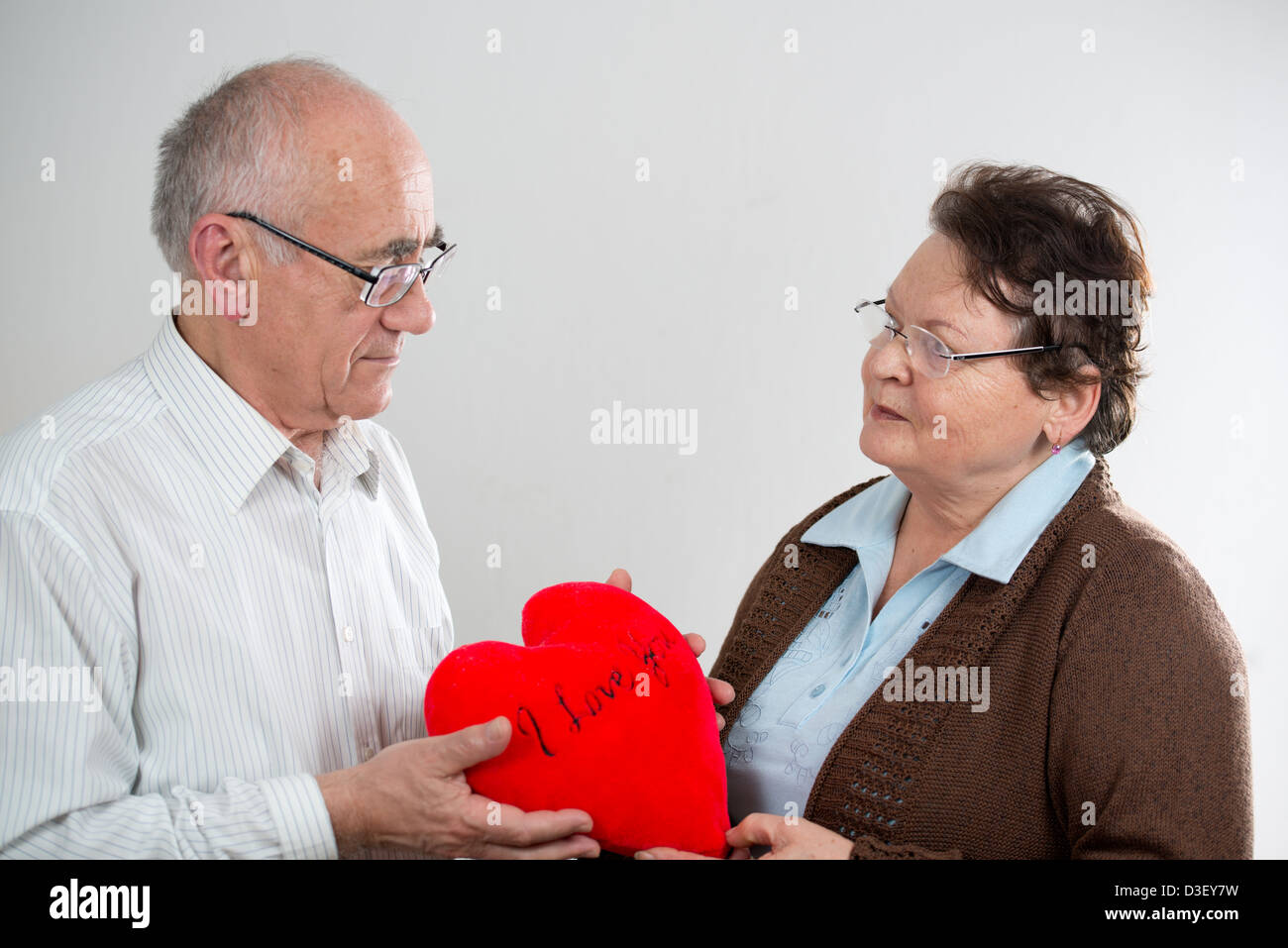 Vecchia coppia con grande cuore rosso che mostra l'amore Foto Stock