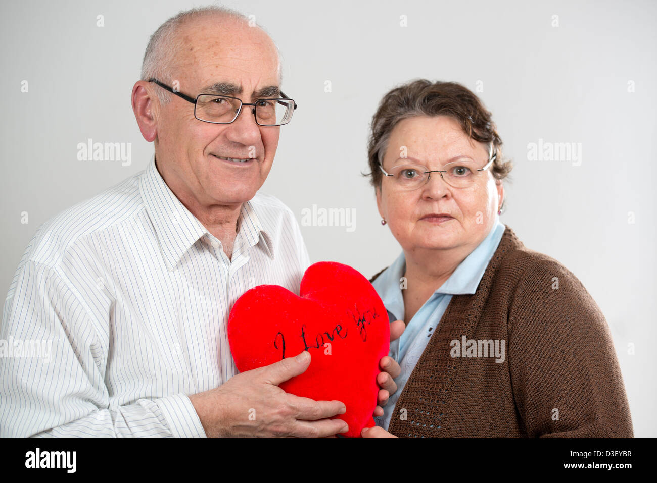 Vecchia coppia con grande cuore rosso che mostra l'amore Foto Stock