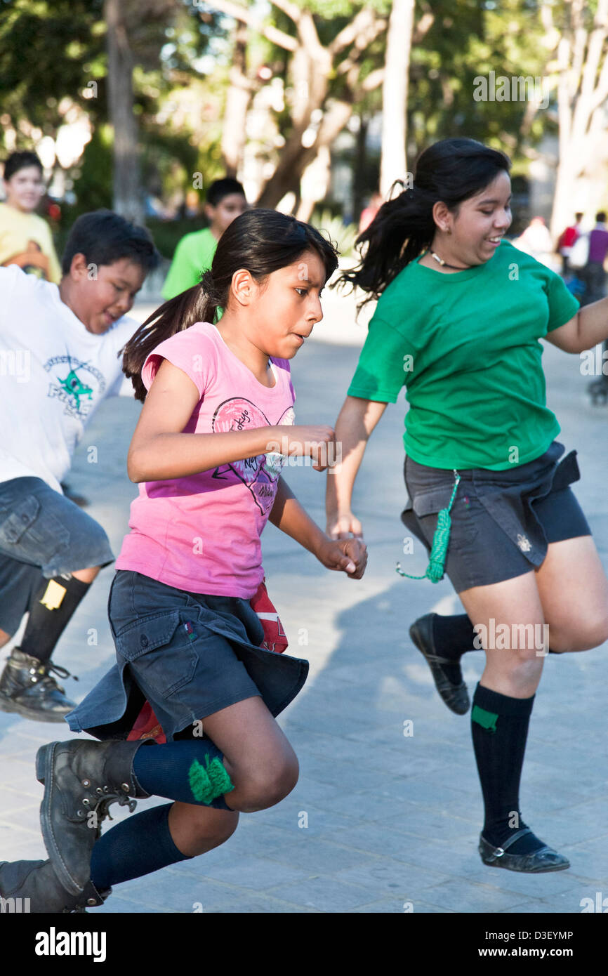 Pre-teen girl & boy scout divertendosi in esecuzione in un fazzoletto zampe staffetta Llano Park Oaxaca Messico Foto Stock