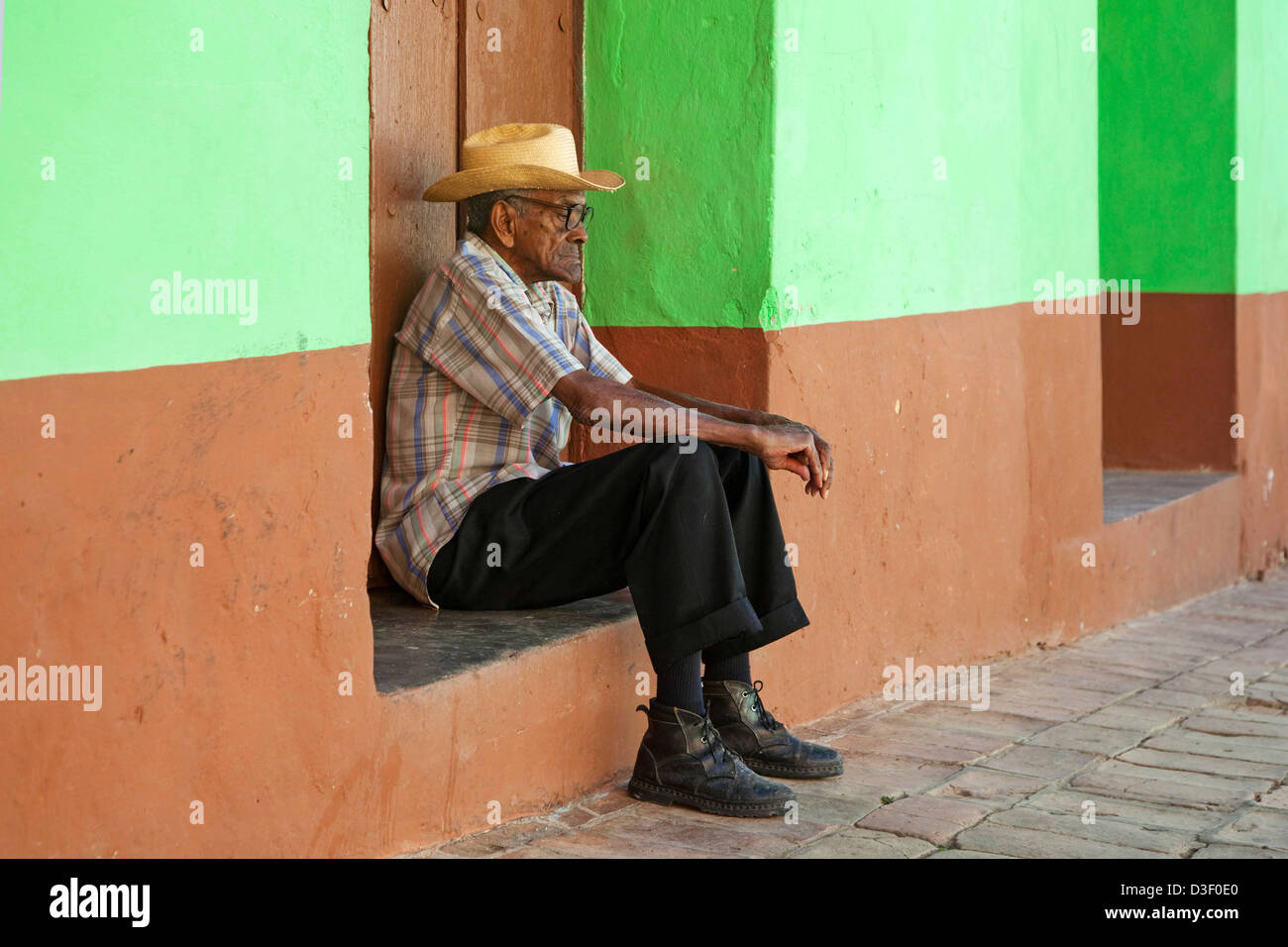 Ritratto di vecchio uomo cubano seduti di fronte color pastello davanti casa per le strade di Trinidad, Cuba Foto Stock