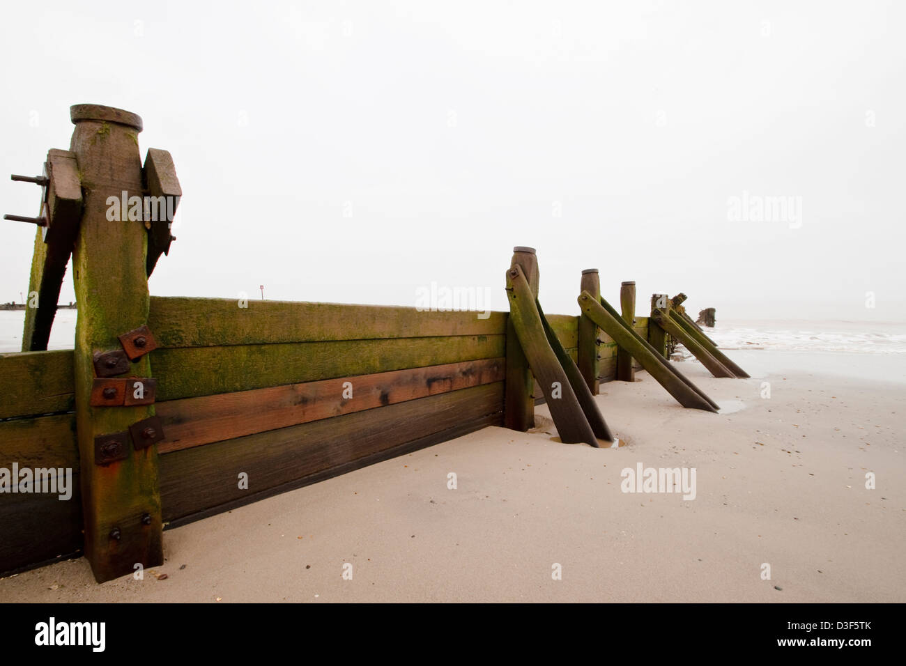 Indossati i frangiflutti in legno su una deserta spiaggia invernale Foto Stock