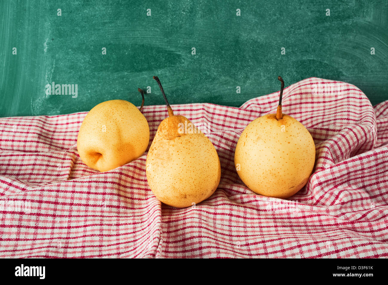 Giallo gustoso frutto di pera su un tavolo da cucina con il rosso e bianco tovaglia a scacchi. Foto Stock