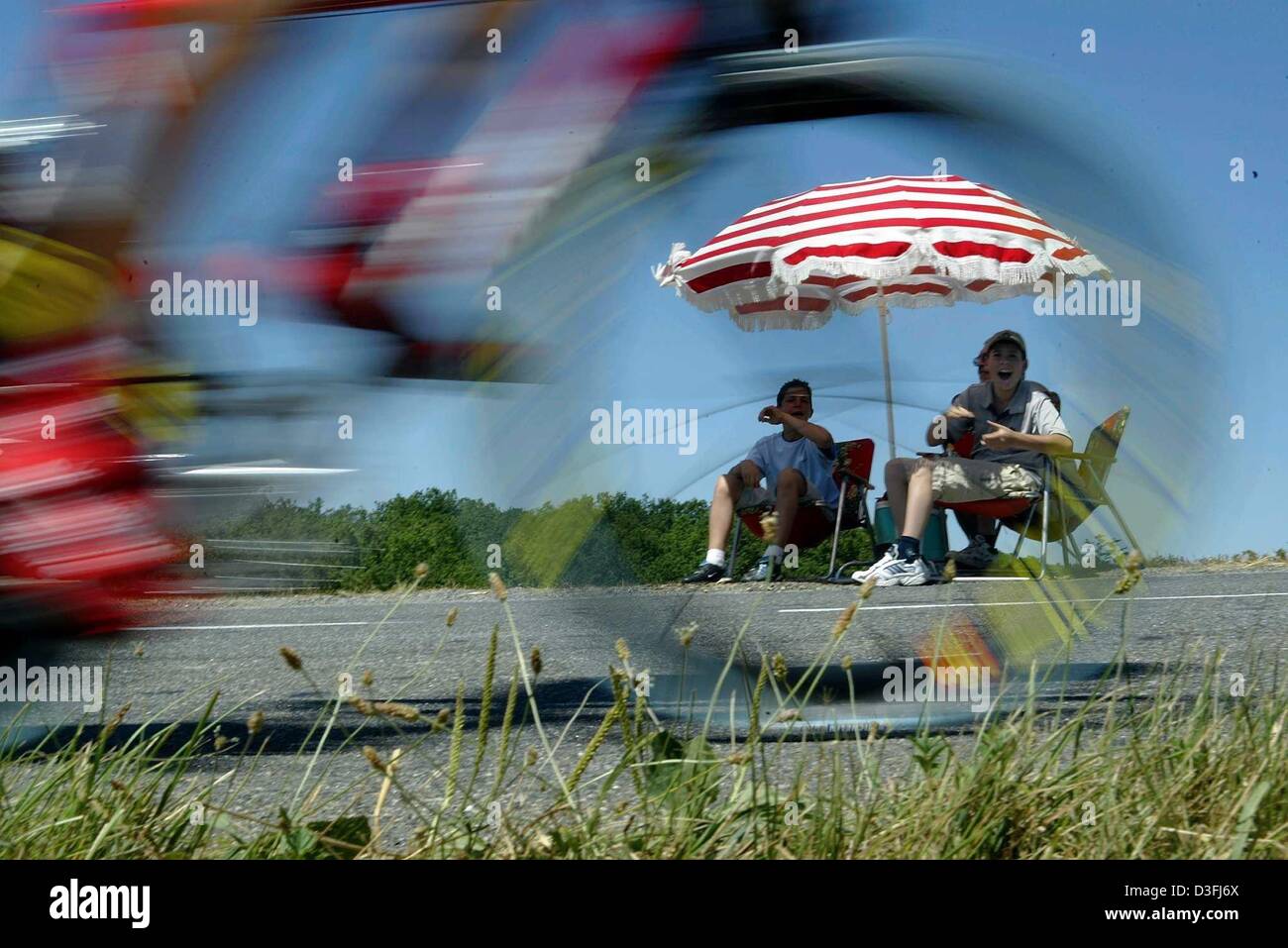 (Dpa) - due spettatori (retro) sedere sulle sedie sotto un ombrellone con grida di incoraggiamento a ciclisti passando da durante il dodicesimo gamba cronometro del Tour de France a Gaillac, Francia, 18 luglio 2003. Il XII gamba copre una distanza di 47 chilometri dalla cittadina francese di Gaillac al cappuccio Decouverte attraverso terreni accidentati con due lunghe piste teso all'inizio e il Foto Stock