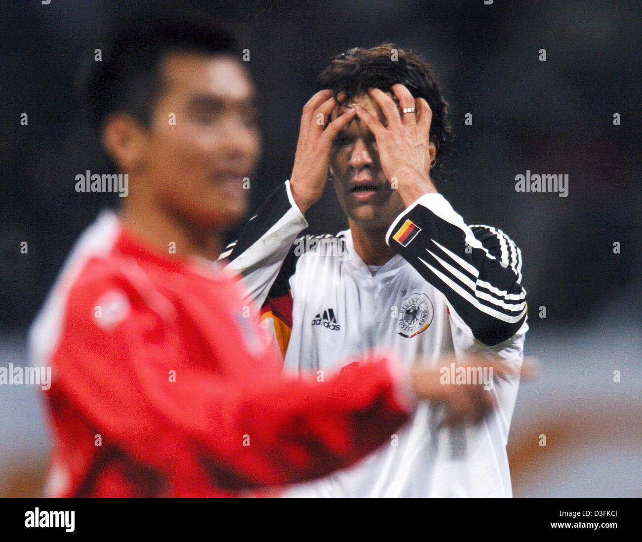 (Dpa) - German National Soccer team capitano Michael Ballack (messa a fuoco) copre il viso con le mani mentre il sud coreano Lee Dong-Gook gesti in primo piano durante il cordiale partita di calcio tra la Germania e la Corea del Sud a Asiad Stadium di Busan, Corea del Sud, domenica 19 dicembre 2004. La Corea del Sud ha vinto 3-1. Foto Stock