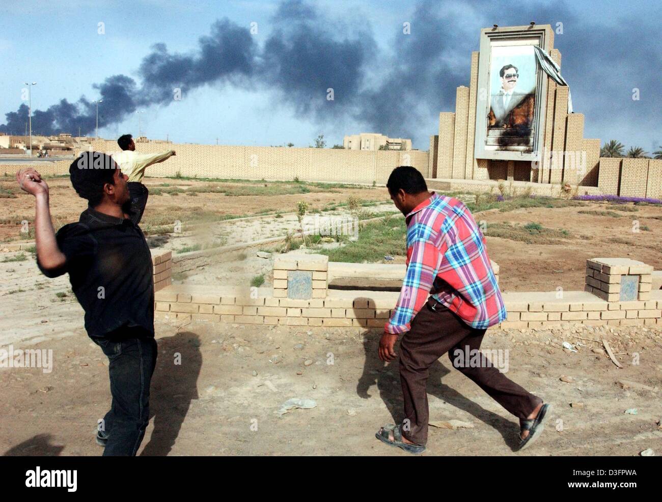 (Dpa) - Furious iracheni scagliare pietre contro una masterizzazione foto di Saddam Hussein a Bagdad, 10 aprile 2003. Dopo la caduta di Baghdad ci sono solo pochi scontri a fuoco nella capitale, ma molti saccheggi. I cittadini iracheni bruciare o distruggere simbolicamente le foto e i monumenti di Saddam, i resti del vecchio regime. Foto Stock