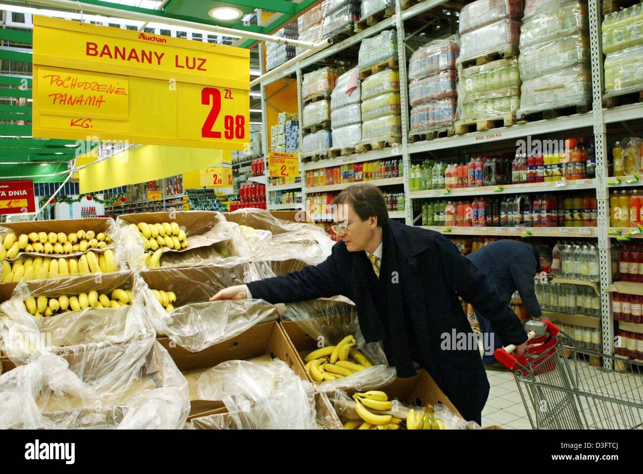 (Dpa) - Un cliente prende le banane da un ripiano al supermercato Auchan Store a Varsavia, Polonia, 15 gennaio 2003. Molti stranieri le catene di supermercati hanno impostato giganteschi centri commerciali in Polonia. Il paese è uno dei dieci per entrare a far parte dell'Unione europea nel 2004. L'Unione europea avrà venticinque Stati membri. Foto Stock