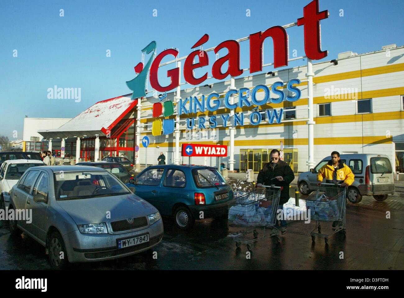 (Dpa) - i clienti con piena carrelli di shopping a piedi attraverso il parcheggio davanti a un supermercato della francese della catena di supermercati "Geant' (gigante) a Varsavia, Polonia, 15 gennaio 2003. Molti stranieri le catene di supermercati hanno impostato giganteschi centri commerciali in Polonia. Il paese è uno dei dieci per entrare a far parte dell'Unione europea nel 2004. L'Unione europea avrà venticinque Stati membri. Foto Stock