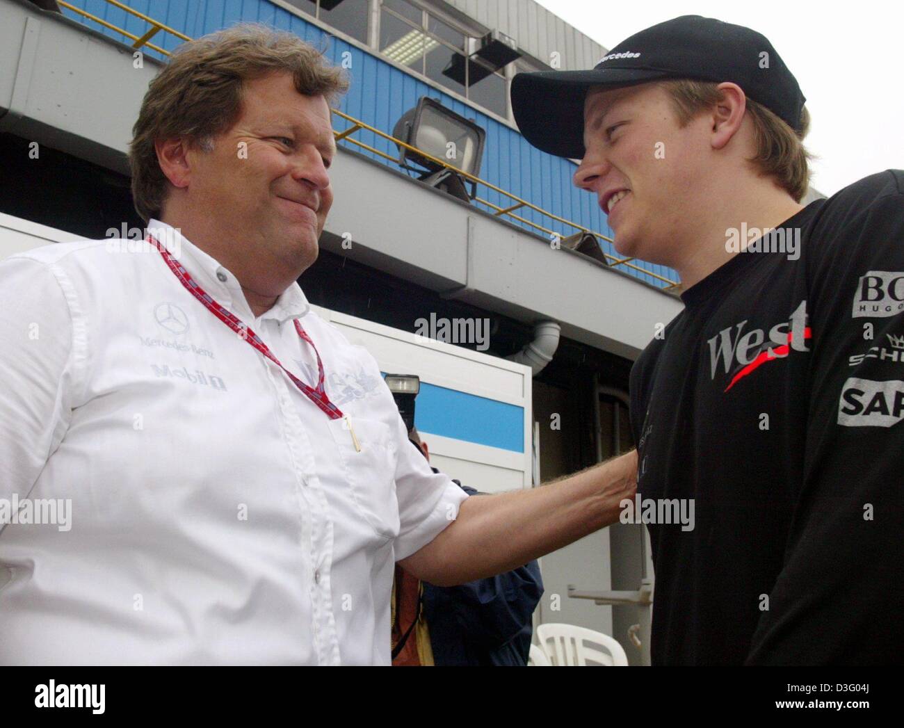 (Dpa) - Norbert Haug (L), il responsabile di Mercedes Motorsport, picchietti la sua Finlandese pilota di Formula Uno Kimi Raeikkoenen sulla spalla dopo la formazione di qualifica sulla pista di Interlagos in Sao Paulo, Brasile, 4 aprile 2003. Foto Stock