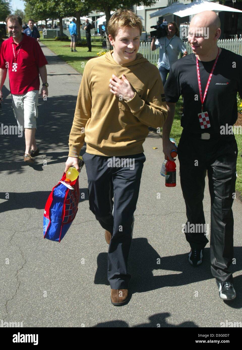 (Dpa) - Finlandese pilota di Formula Uno Kimi Raeikkoenen (C) del team McLaren Mercedes passeggiate arriva presso la pista di Melbourne, Australia, 5 marzo 2003. La stagione di Formula Uno 2003 aprirà questo fine settimana a Melbourne. Foto Stock