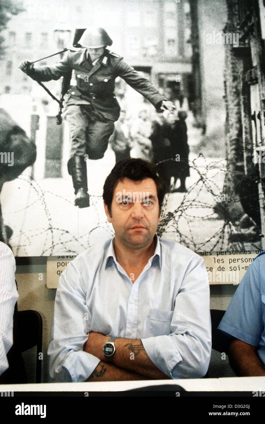 Dpa file) - Conrad Schumann, ex Est soldato tedesco, sta con le braccia  incrociate davanti un poster che lo mostra la fuoriuscita di 25 anni fa nel  1961 attraverso il confine da