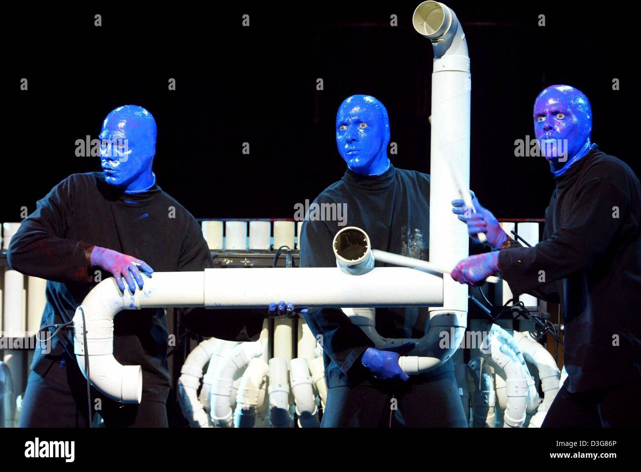 (Dpa) - Tre membri del Blue Man Group, vestiti con i loro costumi dello stadio, che indossa abiti neri e blu facce dipinte, stand con tubi di plastica sul palco durante le prestazioni per la stampa e i mass media presso il Theater am Potsdamer Platz (teatro) di Berlino, 21 ottobre 2003. Il Blue Man Group è un multi-media performance, gruppo che consiste di tre personaggi principali con bald hea Foto Stock